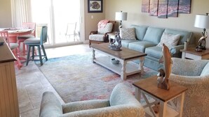 Una sala de estar con sofá, sillones, una mesa de centro y un comedor con sillas y una mesa.
