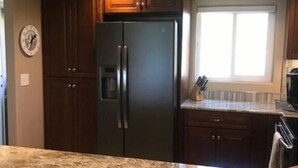 Una cocina con gabinetes de madera oscura, un refrigerador de acero inoxidable y una encimera de granito.