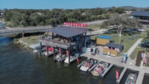 Un restaurant situé au bord de l’eau, doté d’une terrasse couverte et de bateaux amarrés à proximité.