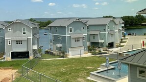 Une rangée de maisons modernes à deux étages, dotées de garages attenants, d’une piscine et offrant une vue sur un lac.