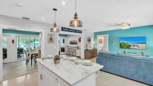 A modern kitchen with a marble island, pendant lighting, and a view of the outdoors. - Bayside Bliss 3 Bedroom Home by RedAwning (Anna Maria)