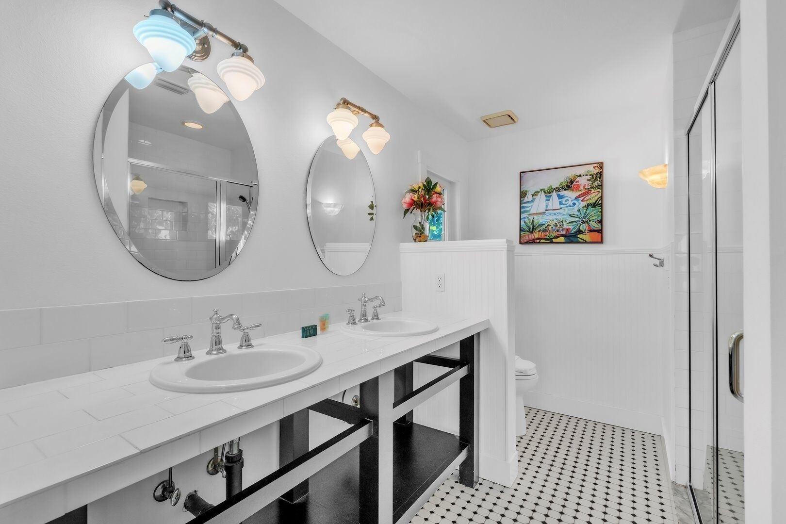 A modern bathroom with two sinks, a large mirror, and a shower.