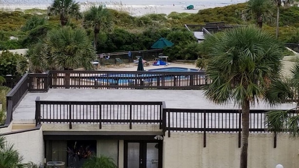Une propriété située en bord de mer, dotée d’une piscine, de palmiers et offrant une vue sur l’océan.