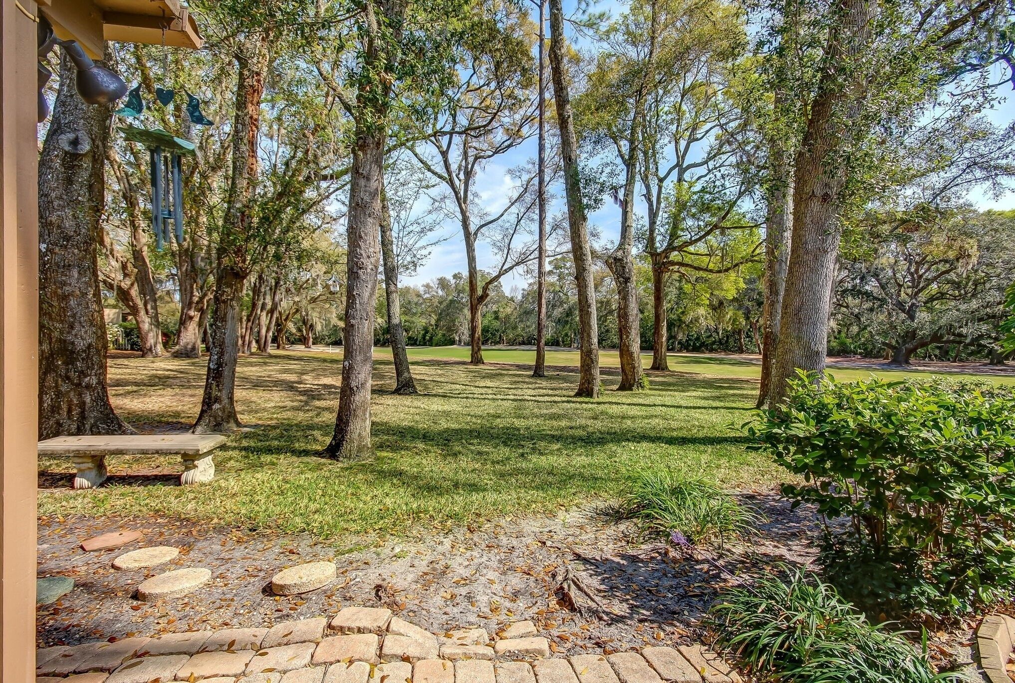 Un parque con un sendero pavimentado, bancos y árboles.