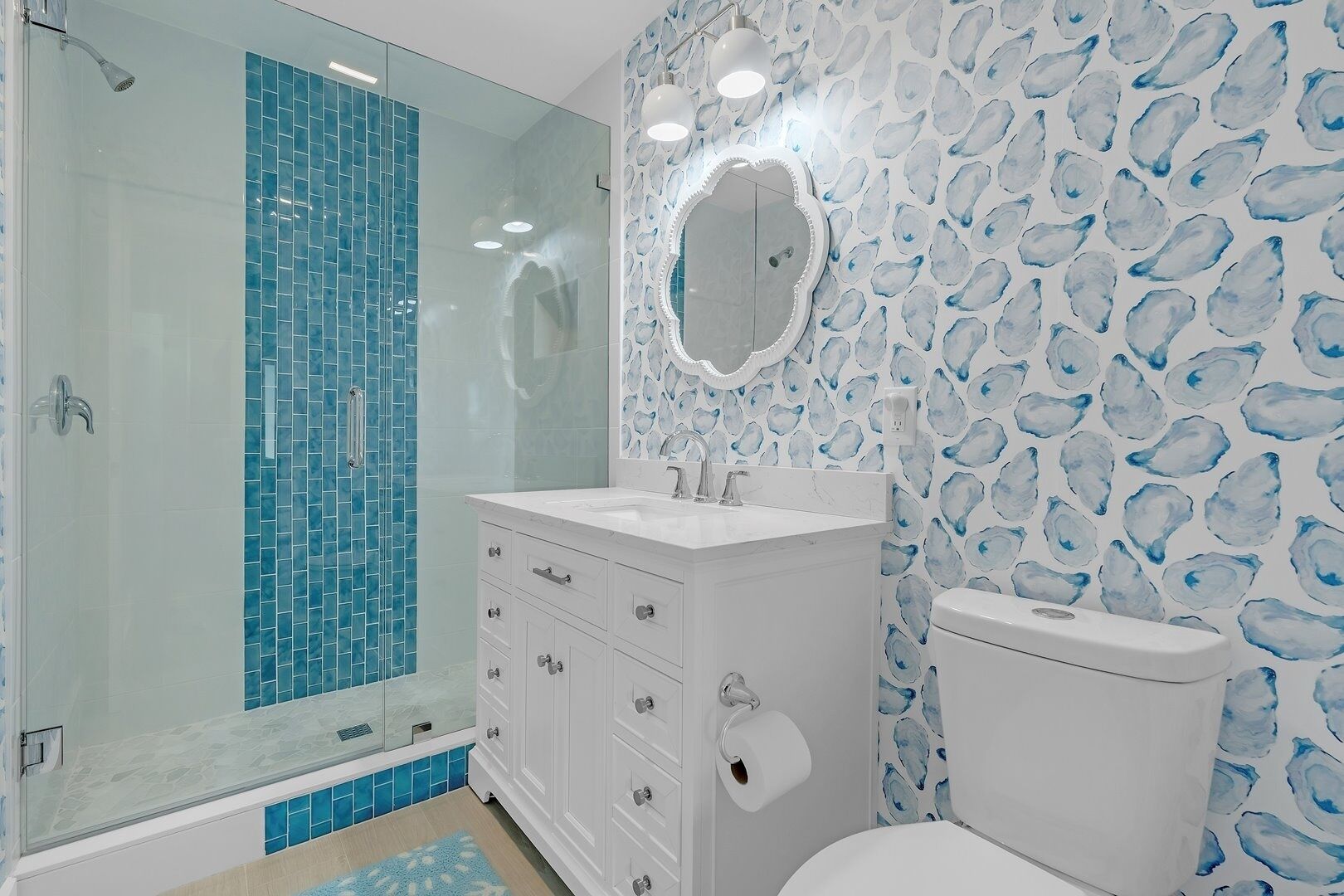 A bathroom with a glass shower enclosure, a white sink, and a toilet.