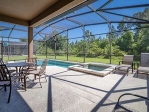 A covered outdoor area with a pool, hot tub, and seating.