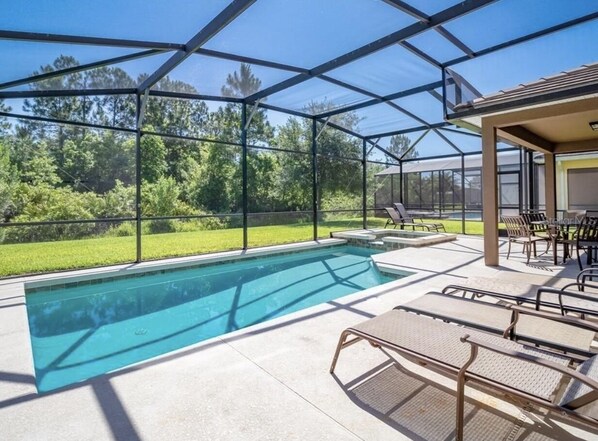 A covered outdoor swimming pool with lounge chairs and a patio area. - Spacious 5 Bedroom villa with private saltwater pool,  huge 100 inch smart TV! (Kissimmee)