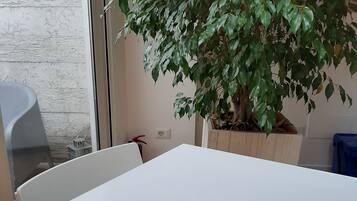 Ein weißer Tisch mit einem Blumentopf und einer roten und weißen Tablettgarnitur.