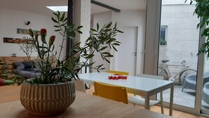 Un espace de vie moderne comprenant un coin repas avec une table en bois et une plante en pot ornée de fleurs.