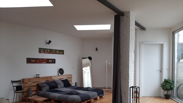 Une chambre moderne avec un lit en bois, un petit bureau et une grande fenêtre.