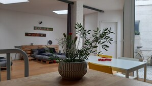 Un salon moderne avec une table à manger en bois, une plante en pot, un canapé et un vélo en arrière-plan.