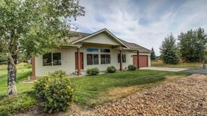 Ein bungalow mit Veranda, Garage und gepflegtem Rasen.