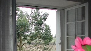 A sliding glass door leading to a patio with a green chair and a wooden fence. - Les Gîtes de Garz Ar Bik Gîte for 2/3 people (Brasparts)