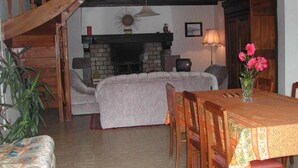 A cozy living room with a fireplace, a dining table, and a staircase. - Les Gîtes de Garz Ar Bik Gîte for 2/3 people (Brasparts)