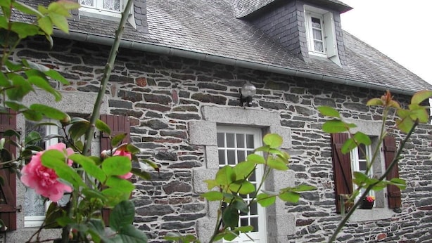 A stone building with a white door and windows, surrounded by greenery. - Les Gîtes de Garz Ar Bik Gîte for 2/3 people (Brasparts)