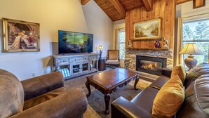 A cozy living room with a fireplace, leather sofas, and wooden beams on the ceiling. - 1 + Loft w/ Views Next to the Village at Mammoth! (Mammoth Lakes)