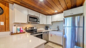 A modern kitchen with white cabinets, stainless steel appliances, and a wooden ceiling. - 1 + Loft w/ Views Next to the Village at Mammoth! (Mammoth Lakes)