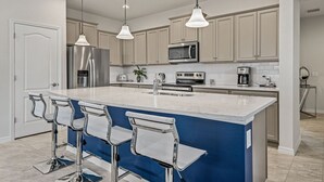 A modern kitchen with a large island, stainless steel appliances, and bar stools.