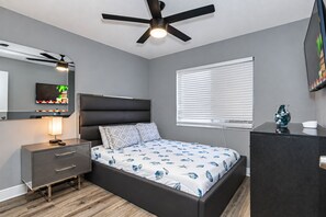 A bedroom with a bed, a TV, a ceiling fan, a window with blinds, and a dresser. - FREE Heated Pool, Sleeps 10, Pinellas Pk | 25 Min to Gulf Beaches (Pinellas Park)