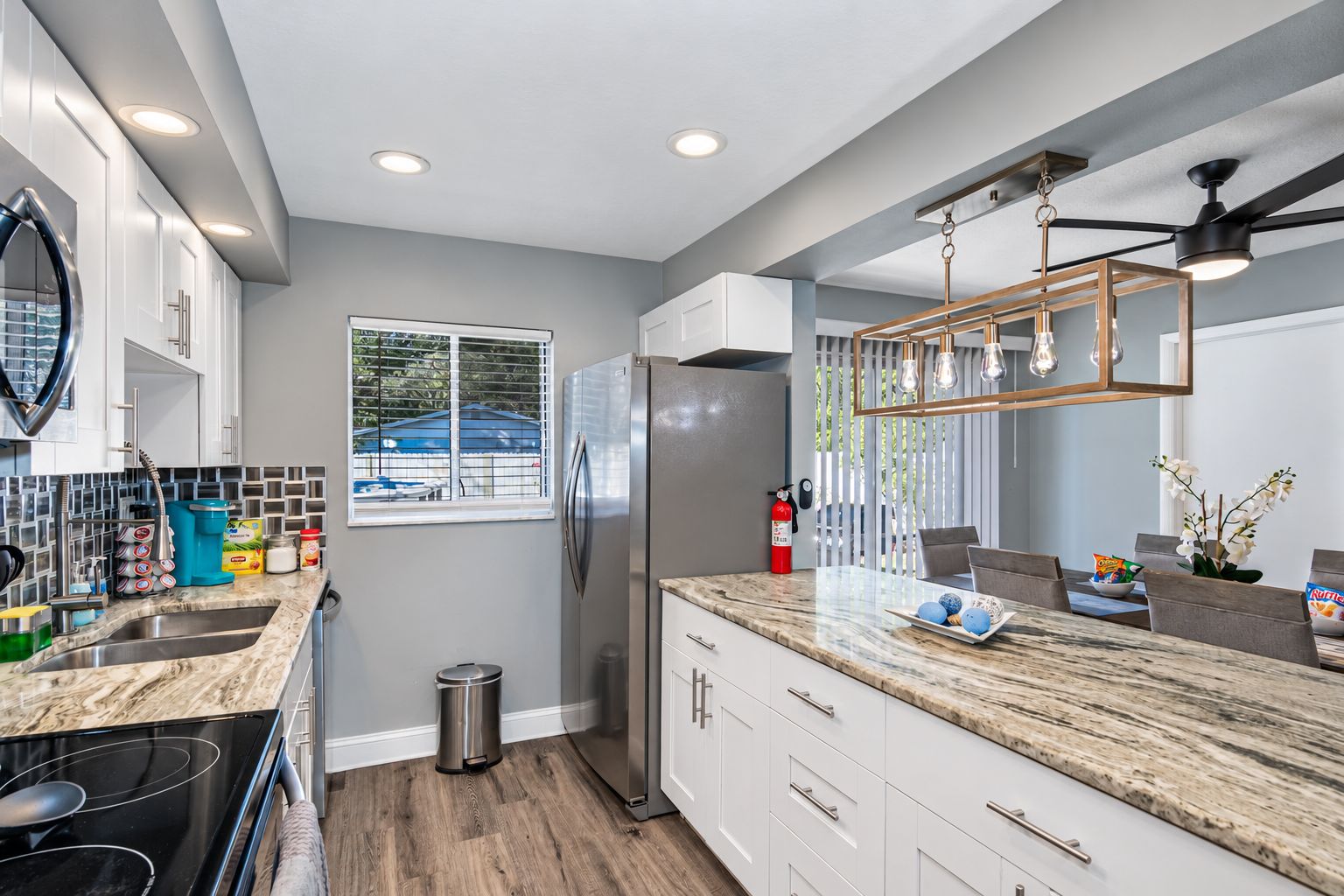 A modern kitchen with a marble countertop, stainless steel appliances, and a window with a view.