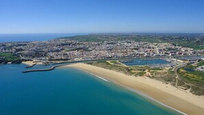 Eine Luftaufnahme einer Küstenstadt mit Strand, einer Marina und einem dicht besiedelten Stadtgebiet.