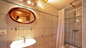 Un baño con lavamanos, espejo, ducha y paredes de azulejos.