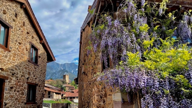 A narrow stone street flanked by traditional buildings with a mountain backdrop. - Apartamentos la Ventana de Mogrovejo (Camaleno)