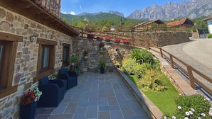 A stone building with a balcony, a stone staircase, and a garden with flowers. - Apartamentos la Ventana de Mogrovejo (Camaleno)