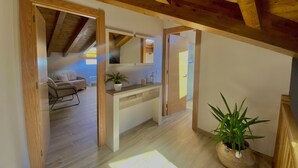A spacious loft with wooden beams, a large mirror, a sofa, and a potted plant. - Apartamentos la Ventana de Mogrovejo (Camaleno)