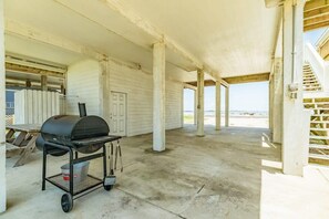 Un espace extérieur abrité, doté d’un barbecue, d’un sol en béton et offrant une vue sur la plage.