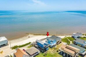 A coastal residential area with beachfront properties, a sandy beach, and a rocky shoreline.