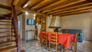 A dining area with a wooden table and chairs, a stone chimney, and a staircase. - CORINNE - 6 people (ST CREPIN ET CARLUCET)