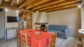 A cozy dining area with a wooden table and chairs, a stone chimney, and a grey sofa. - CORINNE - 6 people (ST CREPIN ET CARLUCET)