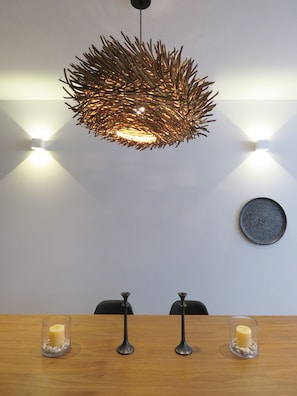 Enjoy meals in this stylish dining area with a central table, pendant light fixture, and warm candlelight.