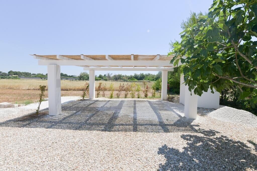 Un espace extérieur abrité, doté d’un sol en gravier et de piliers blancs.