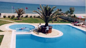 Ein Swimmingpool mit einer zentralen Insel, einer Palme und Flaggen.