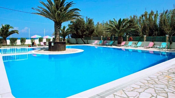 Ein Swimmingpool mit Liegestühlen und Palmen.