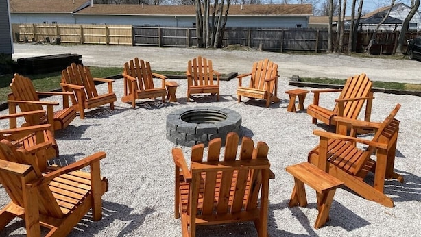 Sillas Adirondack de madera dispuestas en círculo alrededor de un brasero en un espacio al aire libre.