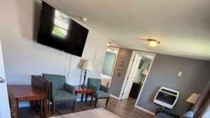 Una sala de estar con un sofá modular grande, un televisor de pantalla plana, una chimenea y un comedor con mesa y sillas.