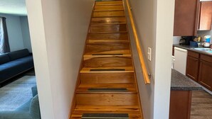 Una escalera de madera con barandilla que lleva a una puerta arriba.