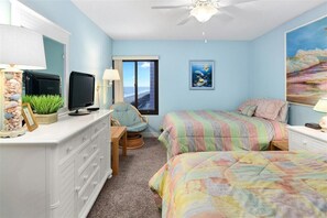 A bedroom with a bed, a TV, a desk, and a chair.