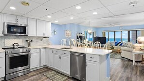 A modern kitchen with white cabinets, stainless steel appliances, and a large island. - Rainbow - Ocean Front 1 Bedroom Condo, Steps to the Beach! (Ocean City)