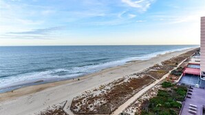 A beach view from a high vantage point, overlooking a sandy beach with sparse vegetation and a clear sky. - Rainbow - Ocean Front 1 Bedroom Condo, Steps to the Beach! (Ocean City)