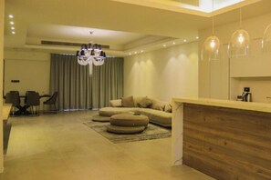 A modern living room with a sofa, ottoman, dining table, chairs, and a chandelier. - Hotel Nordic Resort (Hamala)