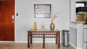 A dining area with a wooden table, a mirror above it, and a trash bin beside it. - Sapphire Dominica-Gorgeous View Walk to beach (St Thomas)
