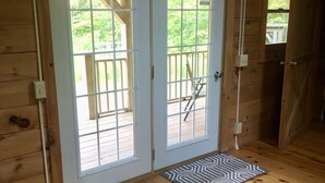 Una cabaña de madera con un balcón y una puerta doble que da a él.