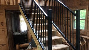 Una escalera de madera con barandillas negras que lleva a una zona superior.