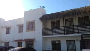 A building with a white facade, multiple windows with metal bars, and a balcony with a black railing. - COMFORT DEPARTMENT (Puerto Vallarta)