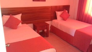 A hotel room with two single beds, a wooden headboard, a small wooden nightstand, and a red curtain. - COMFORT DEPARTMENT (Puerto Vallarta)