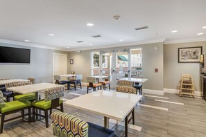 A dining area with tables and chairs, a television, and a view of the outside. - MainStay Suites Columbus near Fort Benning (Columbus)